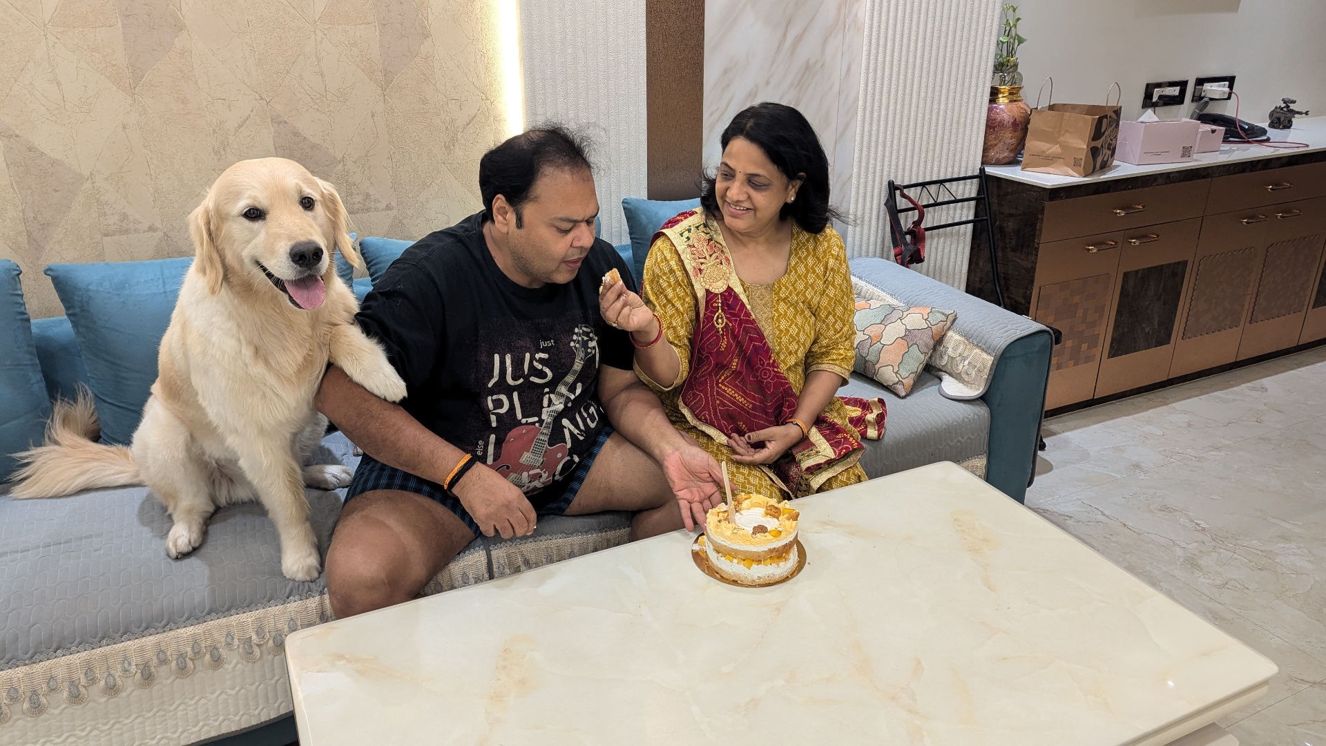 Maa, papa, and Bruno on the sofa with a cake.